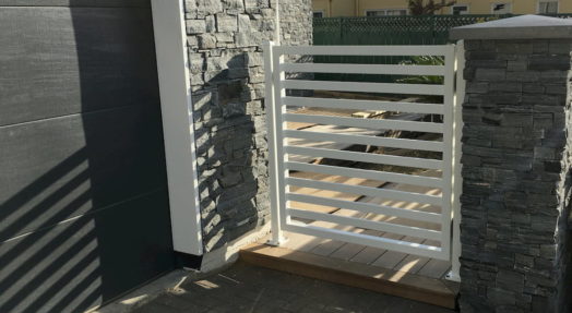 A brick wall and white fence outside a garage