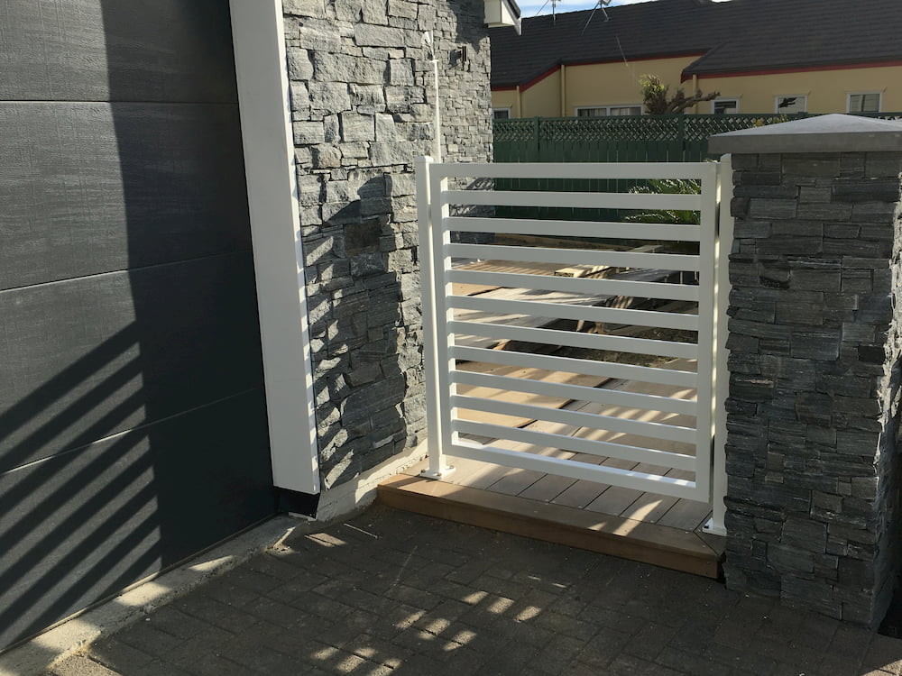 A brick wall and white fence outside a garage